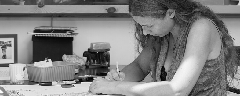 Jiska van der Linden sits at a table drawing patterns